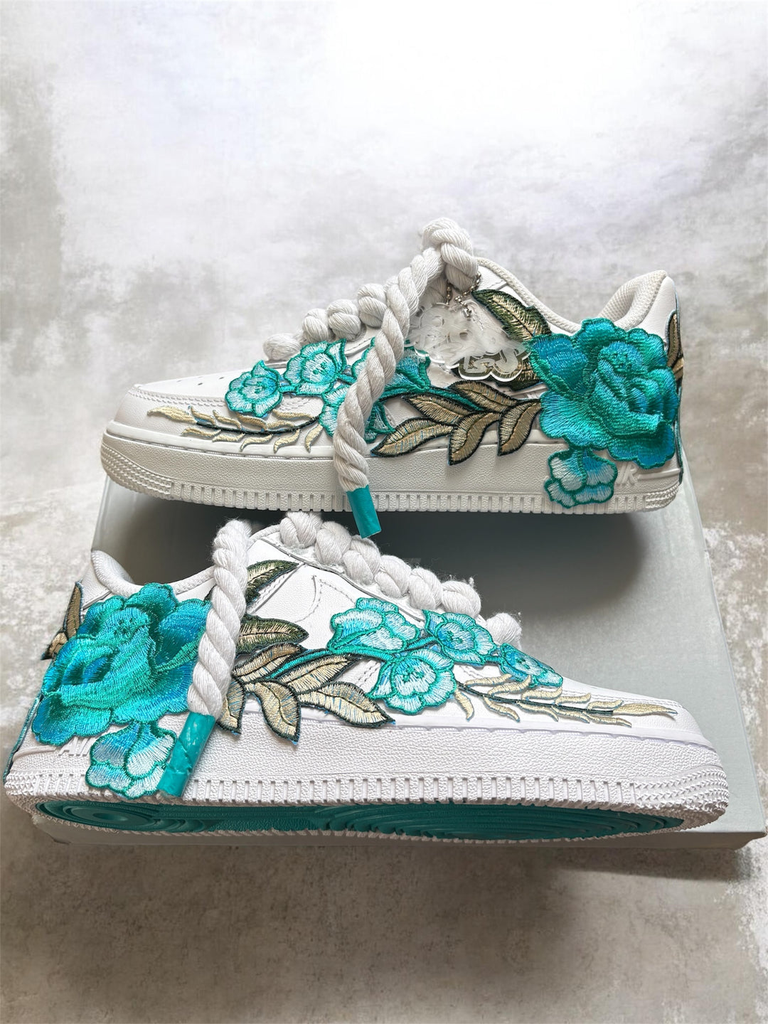 White sneakers with teal floral designs and hard painted bottoms 