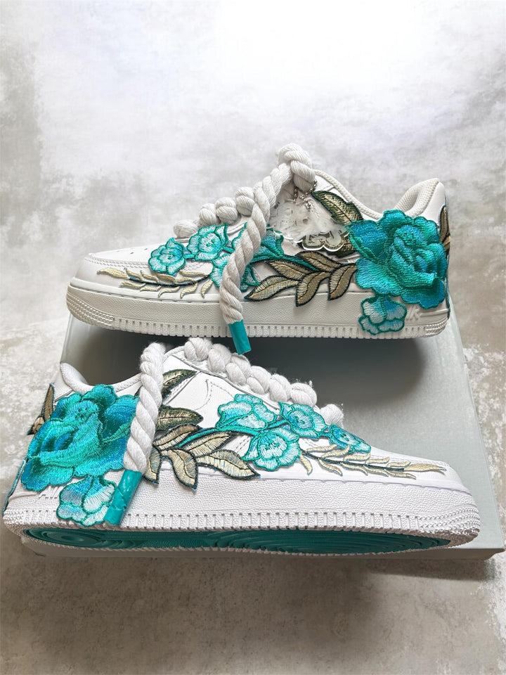 White sneakers with teal floral designs and hard painted bottoms 